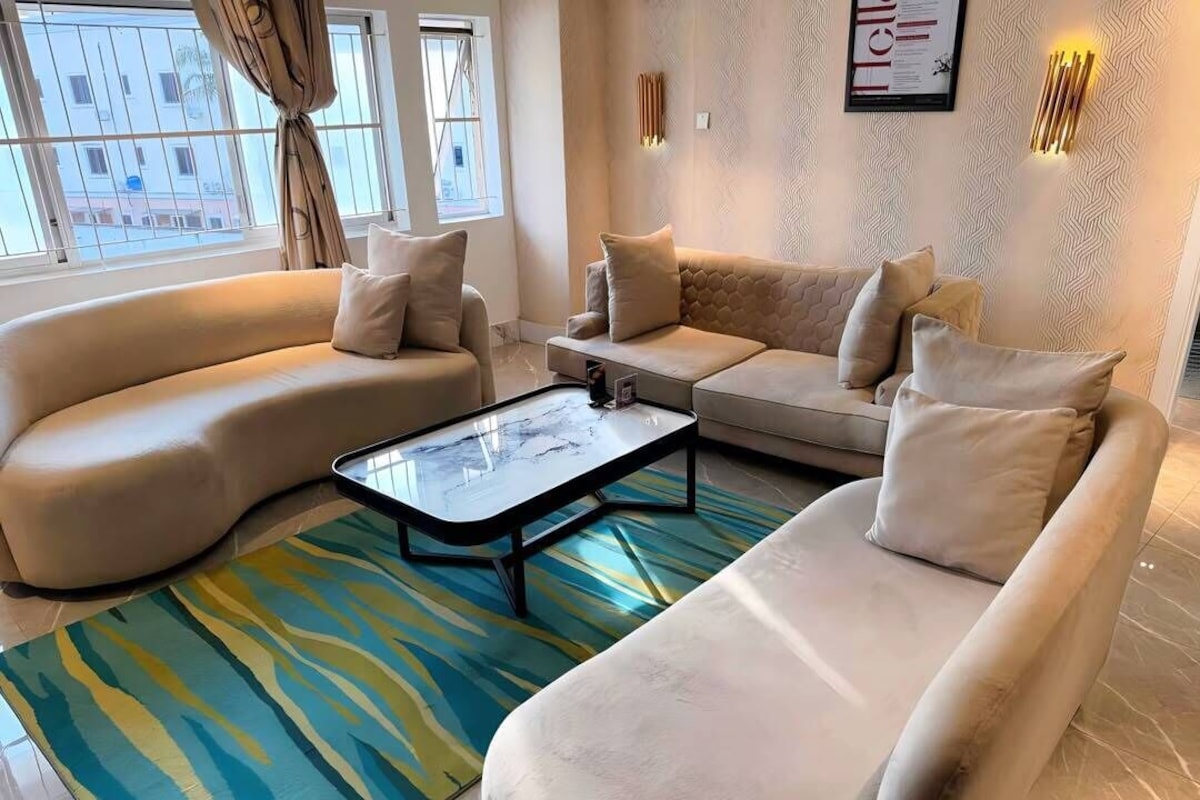 Una sala de estar moderna con un sofá color crema, una mesa de centro y una alfombra estampada.