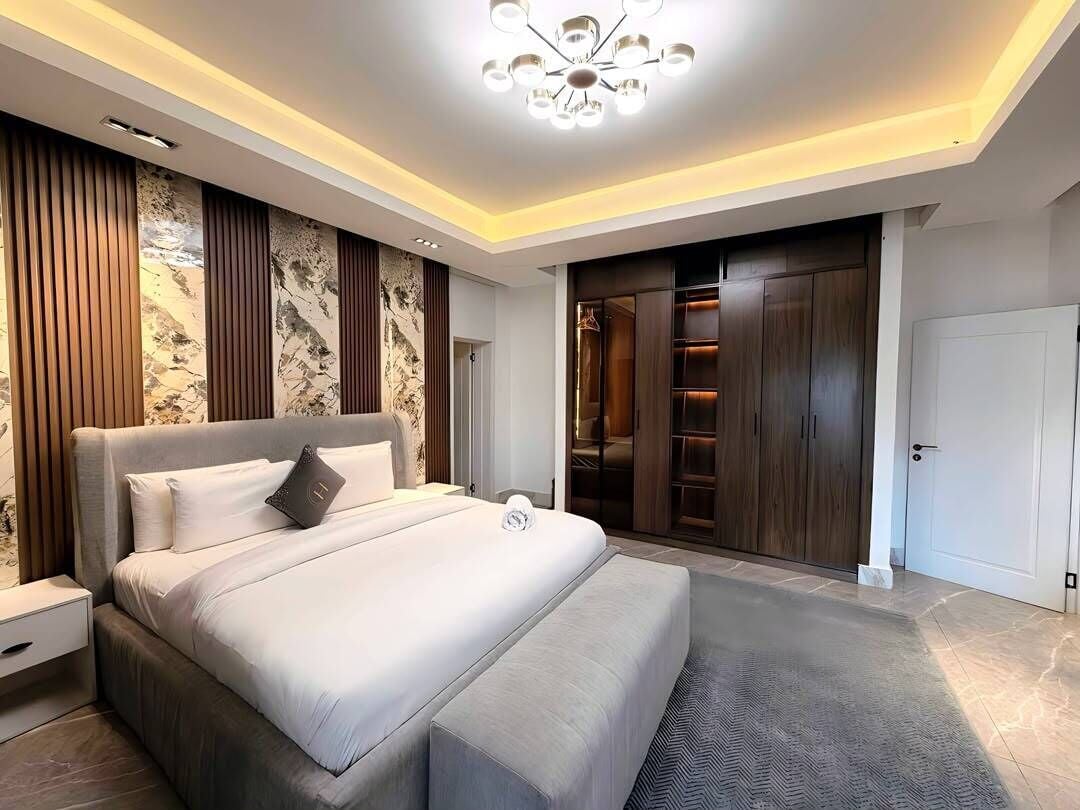 Een moderne slaapkamer met een groot bed, een inbouwkast en een kroonluchter.
