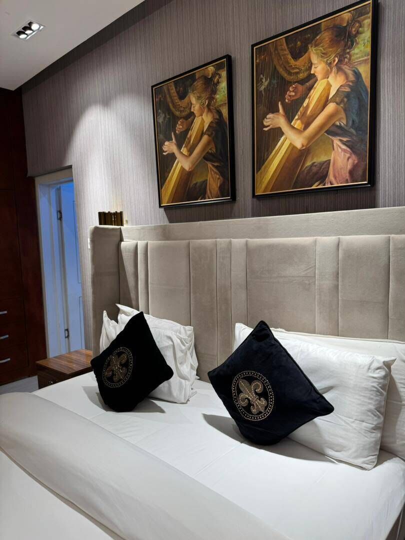 Ein Schlafzimmer mit einem großen Bett, zwei Kissen und zwei Bildern an der Wand.