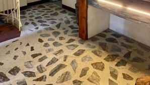 Una cocina con piso de baldosas de piedra, encimera de madera y estante con fotografías enmarcadas.