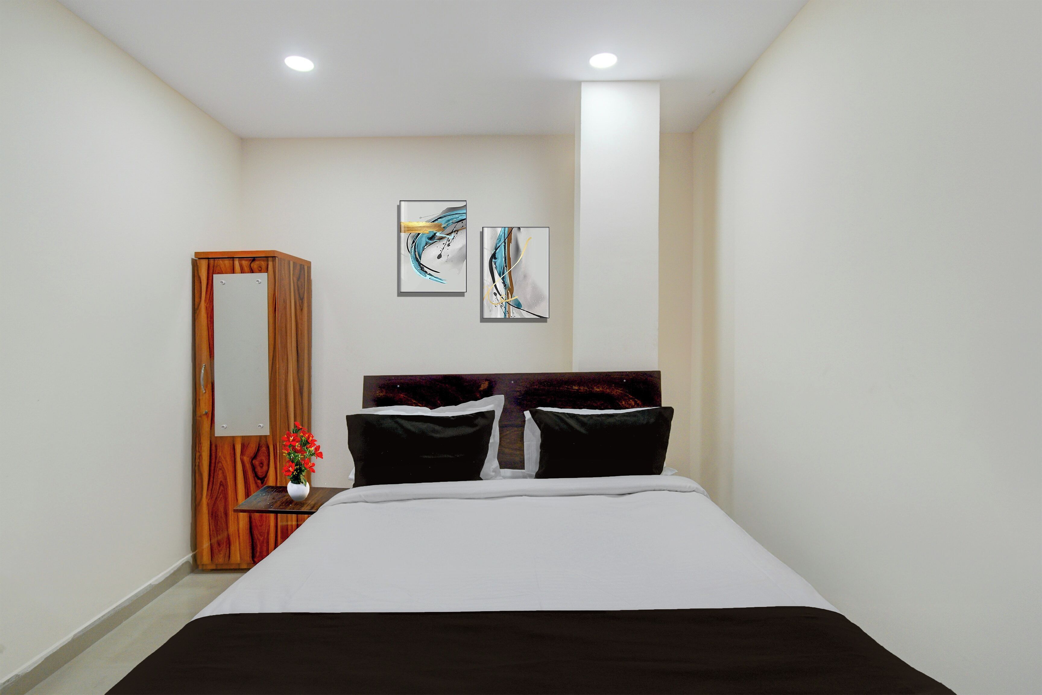 A bedroom with a bed, a wooden wardrobe, and two wall-mounted artworks.