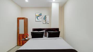 A bedroom with a bed, a wooden wardrobe, and two wall-mounted artworks.