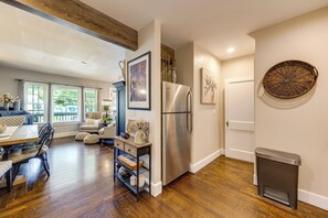 A modern kitchen with a stainless steel refrigerator, wooden flooring, and a dining area with a table and chairs. - Convenient, Cozy Home: Porches, Fire Pit, Office (Meriden)