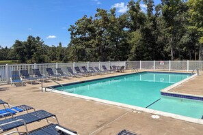 A swimming pool with a white fence, blue lounge chairs, and a clear sky. - 'The Blue Goose Chalet': Your Cozy Up North Escape (Gaylord)