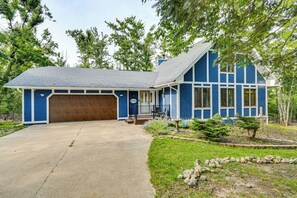 A two-story house with a blue exterior, a wooden garage door, and a front porch with a bench. - 'The Blue Goose Chalet': Your Cozy Up North Escape (Gaylord)