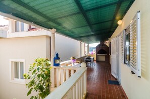 A covered outdoor balcony with a table and chairs, a lantern, and a potted plant. - Apartments Rasica Molunat - One Bedroom Apartment (Konavle)