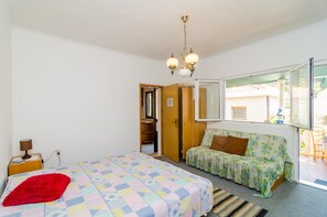 A bedroom with a bed, a sofa, a wardrobe, a mirror, and a window. - Apartments Rasica Molunat - One Bedroom Apartment (Konavle)