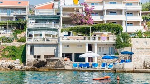 A coastal hotel with multiple balconies, a swimming pool, and sun loungers. - Apartments Rasica Molunat - One Bedroom Apartment (Konavle)