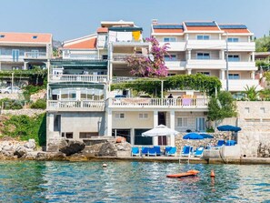 A coastal hotel with multiple balconies, a swimming pool, and sun loungers. - Apartments Rasica Molunat - One Bedroom Apartment (Konavle)
