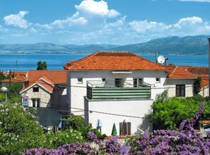 Ein Küstenhaus mit rotem Ziegeldach, einem Balkon und Blick auf das Meer.