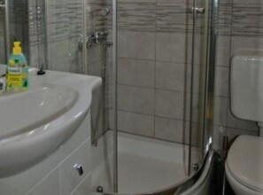 Ein Badezimmer mit einem weißen Waschbecken, einer Duschkabine aus Glas und einer Toilette.