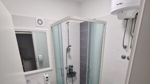 Een moderne badkamer met een douchecabine van glas, een wastafel, toilet en spiegel.