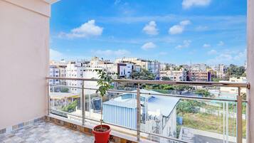Un balcón con planta en maceta, suelo de baldosas y vista panorámica de la ciudad.