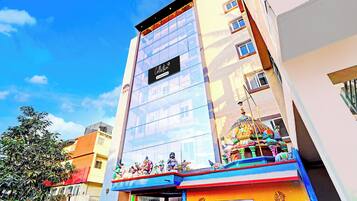A hotel with a glass facade, a sign reading 'Collection', and a colorful entrance with statues.