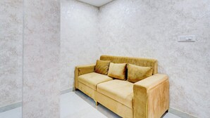 A room with a beige sofa, a light-colored patterned wall, and a ceiling light. - Collection O Brookefield Central (Bengaluru)