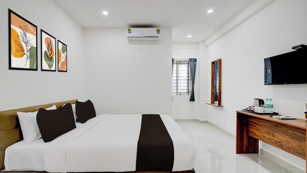 A hotel room with a bed, a desk, a TV, and artwork on the wall. - Collection O Brookefield Central (Bengaluru)