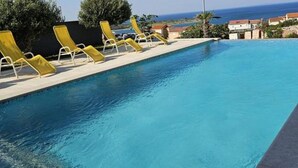 A swimming pool with yellow lounge chairs and a view of the sea. - Villa Marija - Two Bedroom Apartment With Sea View (Novalja)