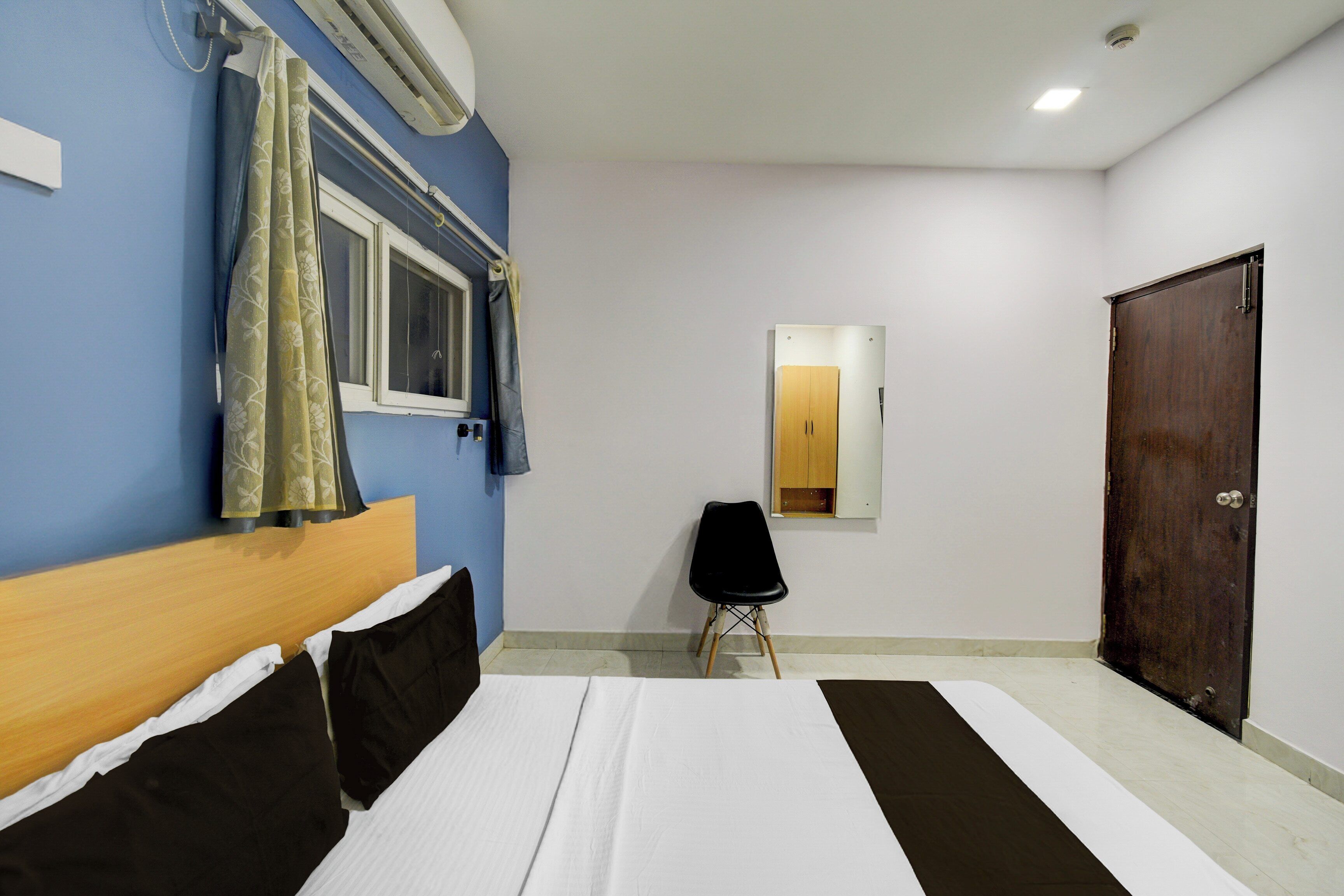 Quarto com cama, cadeira, guarda-roupa e espelho.
