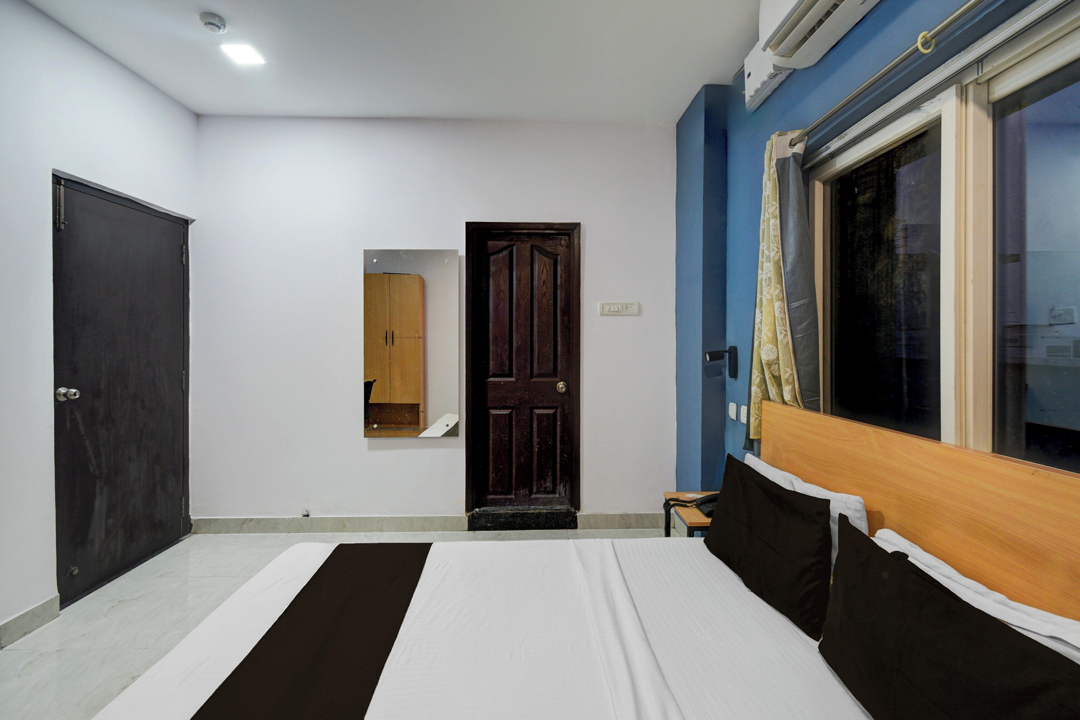 A bedroom with a bed, a wardrobe, a door, and a window.
