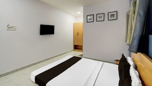 Quarto de hotel com uma cama, televisão de tela plana na parede e um guarda-roupa.