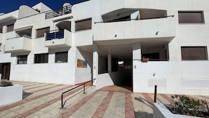 A modern building with multiple balconies, a tiled entrance area, and a sign indicating a restaurant.