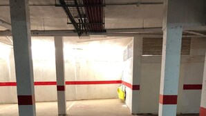 An indoor parking garage with concrete pillars and a yellow safety barrier.