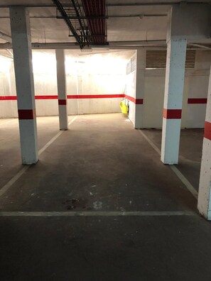 An indoor parking garage with concrete pillars and a yellow safety barrier.