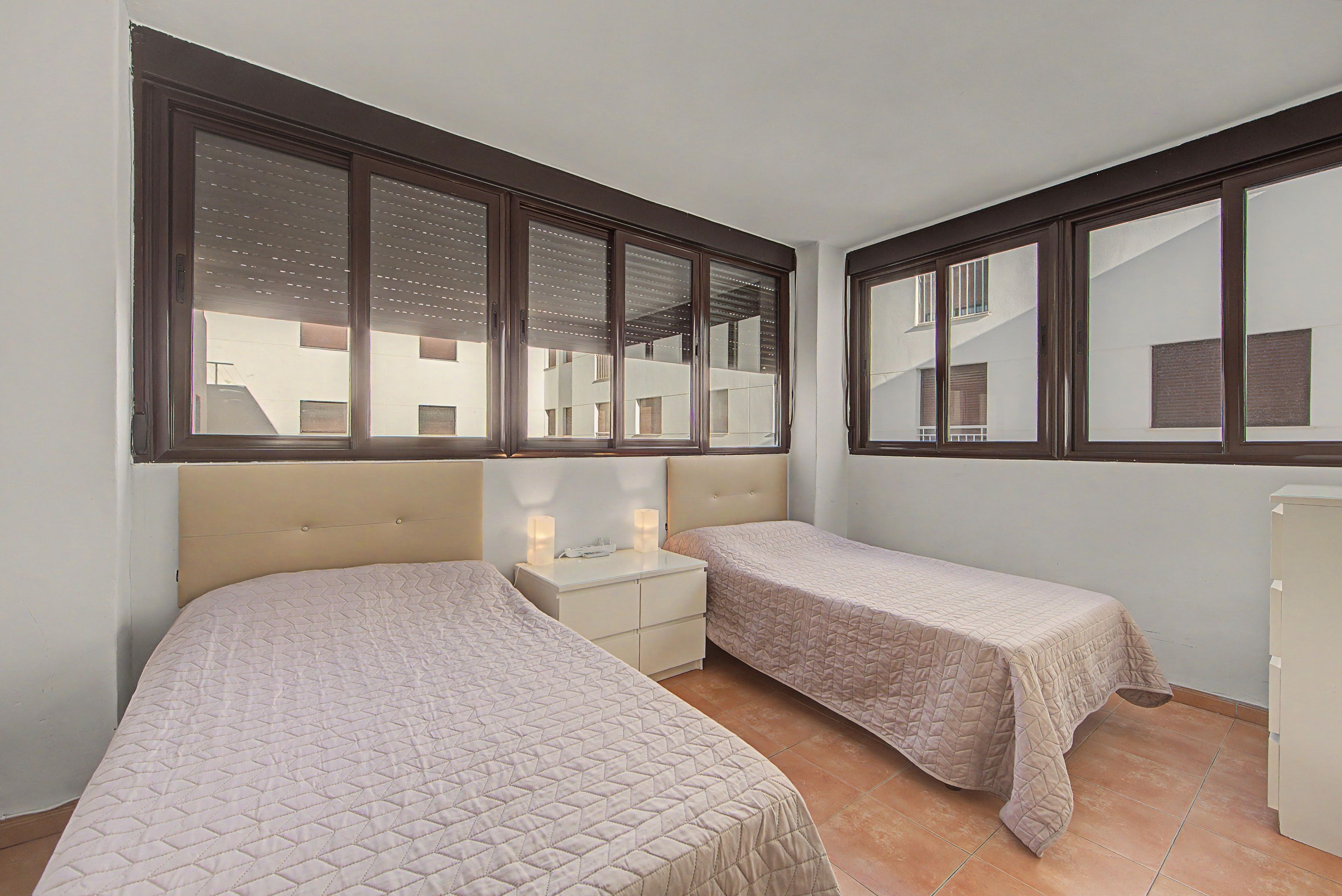 A bedroom with two beds, a nightstand, and a dresser.