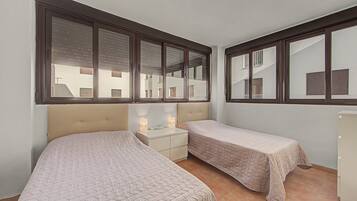 A bedroom with two beds, a nightstand, and a dresser.