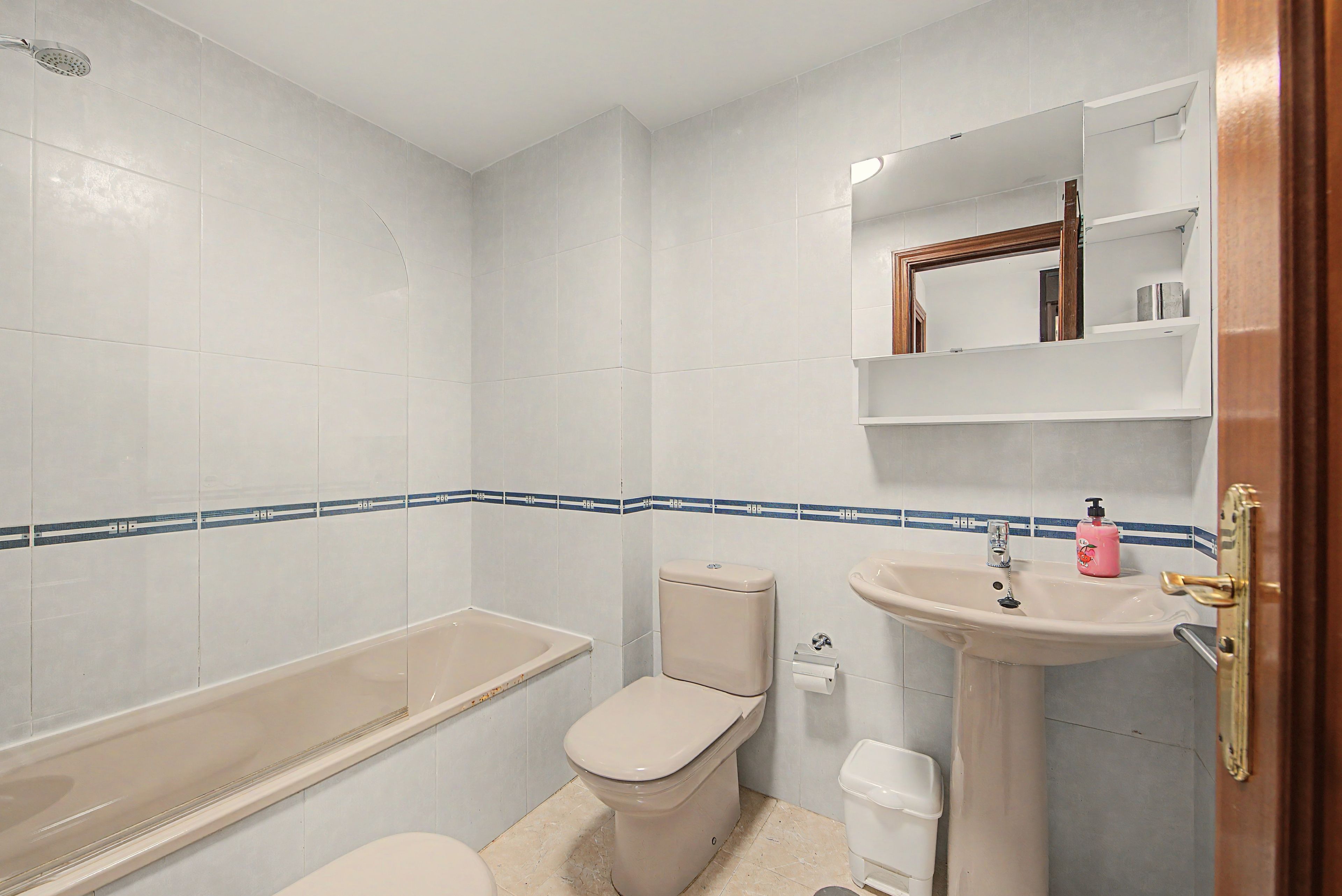 A bathroom with a bathtub, toilet, sink, and a mirror above the sink.