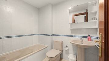 A bathroom with a bathtub, toilet, sink, and a mirror above the sink.