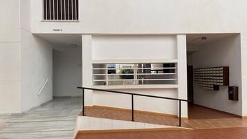 Ein moderner Gebäudeeingang mit Treppe, Geländer und einer Präsentation von Artikeln auf Regalen.