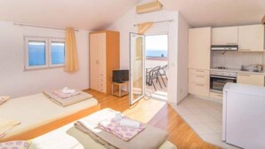 Ein Zimmer mit zwei Betten, einer Küchenzeile und einem Balkon mit Blick.