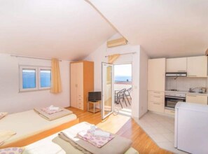 Ein Zimmer mit zwei Betten, einer Küchenzeile und einem Balkon mit Blick.