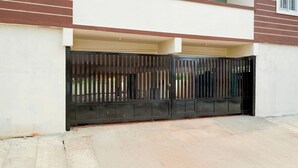 Una entrada con portón cochera a un edificio residencial con techo plano y balcón.