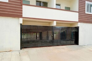 Una entrada con portón cochera a un edificio residencial con techo plano y balcón.