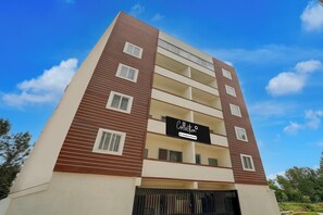A multi-story building with a modern architectural design, featuring a prominent sign on the facade. - Collection O REVA University Rukmini (Bangalore)