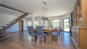 A spacious dining area with a wooden staircase, modern chairs, and a large wooden cabinet. - Villa P - Holiday Home (Sibenik)