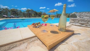 A wooden board with a bottle and glasses on a poolside. - Villa P - Holiday Home (Sibenik)