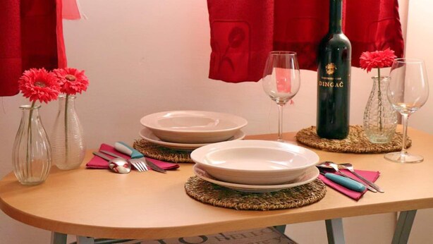 A table set with plates, cutlery, a wine bottle, and vases with flowers. - Apartments Clementina Sunrise-standard Studio Apartment (Orebic)