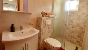 A bathroom with a sink, toilet, and a glass shower enclosure. - Apartments Clementina Sunrise-standard Studio Apartment (Orebic)