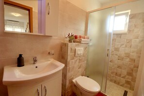 Ein Badezimmer mit Waschbecken, Toilette und einer Duschkabine aus Glas.