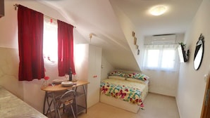A compact bedroom with a bed, a small table, and a chair. - Apartments Clementina Sunrise-standard Studio Apartment (Orebic)