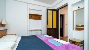 A hotel room with a bed, a bedside table, a lamp, a mirror, and a door with a towel rack. - Apartments Klis -two-bedroom Apartment With Terrace (Zupa dubrovacka)