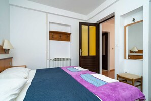 A hotel room with a bed, a bedside table, a lamp, a mirror, and a door with a towel rack. - Apartments Klis -two-bedroom Apartment With Terrace (Zupa dubrovacka)