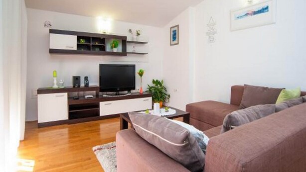 A living room with a flat-screen TV, a sofa, a coffee table, and a small plant. - Apartment Spalato - Three Bedroom Apartment With Terrace (Bibinje)