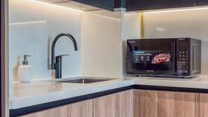 A modern kitchen with a stainless steel sink, a black faucet, and a Hisense microwave oven. - Marina Living Residences - Dubai Marina (Dubai)