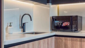 Eine moderne Küche mit Spüle aus Edelstahl, einem schwarzen Wasserhahn und einem Hisense Mikrowellenofen.