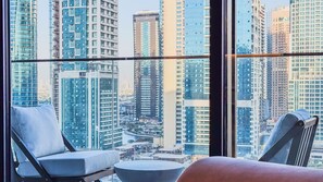 Ein modernes Hotelzimmer mit großem Fenster und Blick auf eine Skyline aus Hochhäusern.