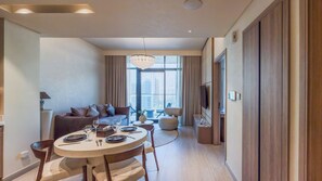 A modern living room with a dining area, large windows, and a view of the city. - Marina Living Residences - Dubai Marina (Dubai)